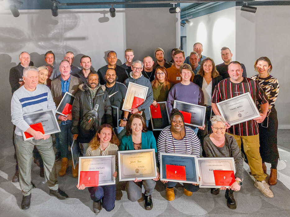 Große Gruppe von Mitarbeitenden in Würzburg mit Urkunden für 10 Jahre Betriebszugehörigkeit.